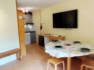 a kitchen with a table with a tv on the wall at 2 Pièces, skis aux pieds, proche commerces avec balcon. Capacité 6 pers, animaux non admis - FR-1-771-11 in Les Adrets