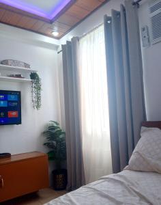 a bedroom with a bed and a window with curtains at Mistow MarinaSpatial Dumaguete in Piapi +10 photos