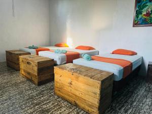 three twin beds in a room with wooden chests at Nicte Guesthouse in Flores