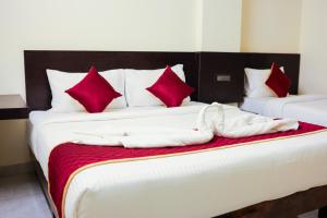 Dos camas en una habitación con almohadas rojas y blancas. en Grace Vista, en Thanjāvūr