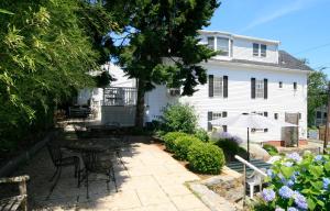 um pátio com uma mesa e cadeiras em frente a uma casa em Eagle House Motel em Rockport