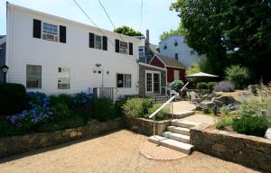 Casa blanca con pared de piedra y patio en Eagle House Motel, en Rockport