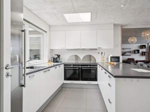a kitchen with white cabinets and black counter tops at 5 star holiday home in Glesborg in Glesborg +37 photos