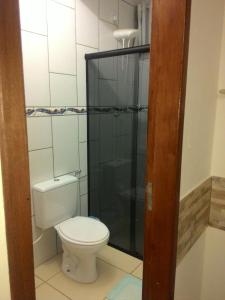 a bathroom with a toilet and a glass shower at Pousada Vó Nita in Penha