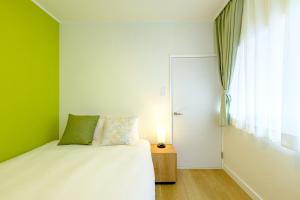 東京にあるLife Town Nishirokugoの緑の壁のベッドルーム1室(白いベッド1台付)