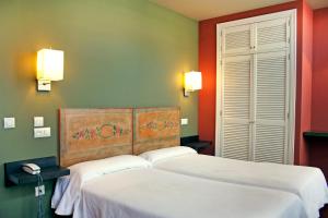 two beds in a room with red and green walls at Hotel La Colmena in Luarca