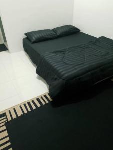 a black bed with a black blanket and a black rug at Nazana Homestay in Batu Gajah