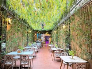 a restaurant with tables and chairs and plants on the wall at Capsule Riverside in Ho Chi Minh City