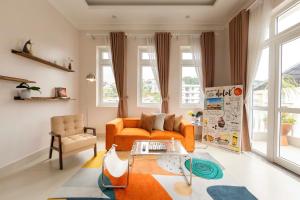 a living room with an orange couch and a chair at Mây Hoa Tiên Villa - House in Da Lat