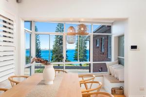 a dining room with a table and a large window at Beach-Front Apartments in Sydney