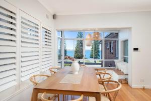 a dining room with a table and chairs and a window at Beach-Front Apartments in Sydney