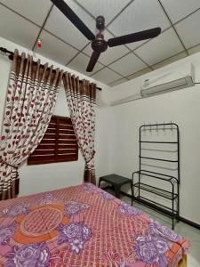 une chambre avec un lit et un ventilateur de plafond dans l'établissement Shara HomeStay, à Trincomalee