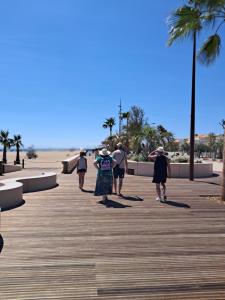 a group of people walking down a boardwalk near the beach at Appartement refait à neuf, climatisé, en rez-de-jardin, à 30 secondes de la plage in Narbonne-Plage