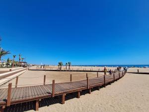 a boardwalk on a beach with people walking on it at Appartement refait à neuf, climatisé, en rez-de-jardin, à 30 secondes de la plage in Narbonne-Plage +7 photos