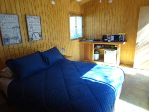 a bedroom with a blue bed in a wooden wall at Cabañas Los Sauzales del Elqui in Pisco Elqui