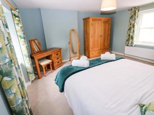 a bedroom with a bed and a dressing table and a mirror at Peace Cottage in Darlington
