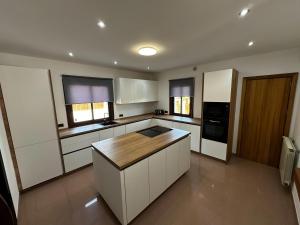 Una cocina con gabinetes blancos y una encimera de madera. en Villa Ibiza Retreats, en Puig D’en Valls