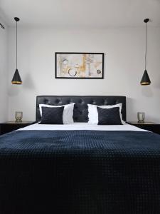 a bedroom with a large black bed with pillows at Apartmani i sobe Gromilovic in Sombor +71 photos