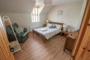 a bedroom with a bed and a couch and a chair at Corner Cottage in Castlerock