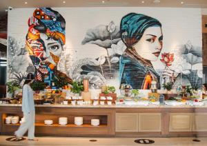 a man walks past a store with a mural of two women at Ocean Pearl Residence Nha Trang in Nha Trang