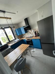 a kitchen with a wooden table and blue cabinets at T2 moderne proche centre avec balcon et wifi in Saint Lo