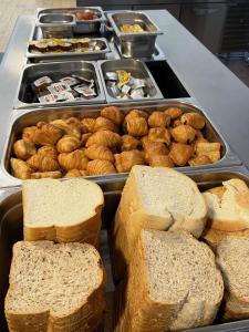a buffet with bread and pastries and trays of food at Horizon Hostel in Bredene