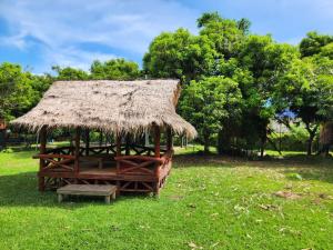 a grass hut with a bench in a field at Surya Kep - Le Soleil Kep in Kep