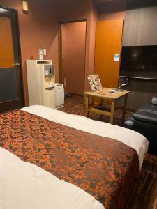 a hotel room with a bed and a table and a tv at Carnet (Adult Only) in Amagasaki