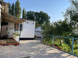 a porch of a house with a fence and flowers at Azem Guest House in Kasymbek