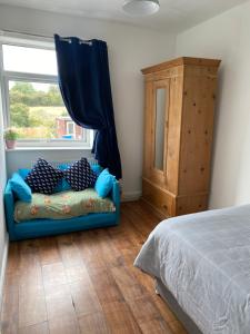ein Schlafzimmer mit einem blauen Sofa vor einem Fenster in der Unterkunft Hilltop Cottage in Renishaw