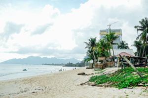 a beach with palm trees and a building at Tropical Langkawi in Pantai Cenang +49 photos