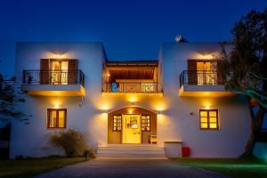 a white house with a yellow door at night at Artemida Pansion Georgioupolis in Kournás