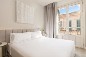 a white bedroom with a large bed and a window at Coeo Frailes Design Apartments in Málaga +28 photos