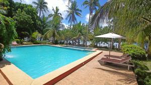a large swimming pool with an umbrella and a chair at Suki Beach Resort "D" Standard Aircon Room in Santa Magdalena