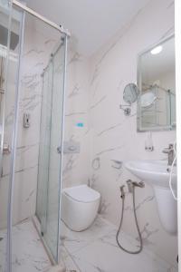 a white bathroom with a shower and a toilet and a sink at Westhills Hotel in Tbilisi City