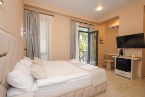 a bedroom with a large white bed and a television at Westhills Hotel in Tbilisi City