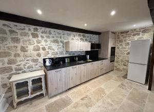 una cucina con pareti in pietra e frigorifero bianco di Le Logis de la Bastide a Lauzerte