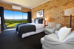 a bedroom with a bed and chairs and a brick wall at Maleny Views Motel in Maleny
