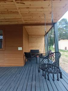 a porch with two chairs and a swing at Amber Coast - Domek nr 4 in Jantar +9 photos