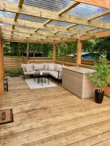 a patio with a couch under a wooden pergola at Heerlijke ruime stacaravan met overdekte veranda en omheinde tuin ''Casa Elvina'' in Eext