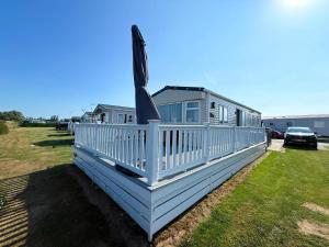 a house with a white deck with a flag at Stunning Caravan With Wifi & Decking At St Osyth Beach In Essex Ref 28007Sv in Clacton-on-Sea