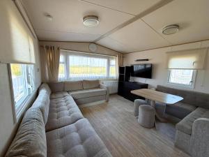 a living room with a couch and a table at Stunning Caravan With Wifi & Decking At St Osyth Beach In Essex Ref 28007Sv in Clacton-on-Sea