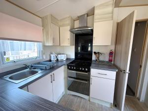 a kitchen with a sink and a stove top oven at Stunning Caravan With Wifi & Decking At St Osyth Beach In Essex Ref 28007Sv in Clacton-on-Sea