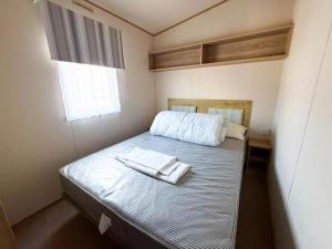 a small bedroom with a bed with a towel on it at Stunning Caravan With Wifi & Decking At St Osyth Beach In Essex Ref 28007Sv in Clacton-on-Sea +12 photos