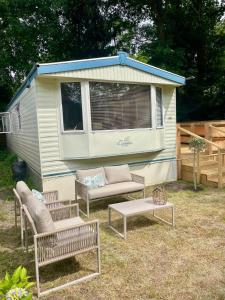 a trailer with benches and a table in a yard at Heerlijke ruime stacaravan met overdekte veranda en omheinde tuin ''Casa Elvina'' in Eext