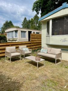 three couches and a table in front of a trailer at Heerlijke ruime stacaravan met overdekte veranda en omheinde tuin ''Casa Elvina'' in Eext +15 photos