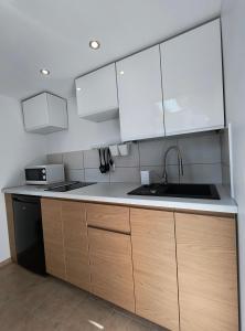 a kitchen with white cabinets and a sink at Pokoje Goscinne SALOMEA in Karwia