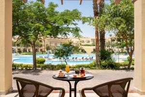 a table with food and drinks on a patio with a pool at Mövenpick Hotel Cairo - Media City in 6th Of October