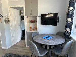 a room with a table and chairs and a tv at Blue Skies in Brading