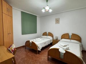 a bedroom with two beds and a green board on the wall at Alojamiento Casa Pepa en el Centro de Calasparra in Calasparra